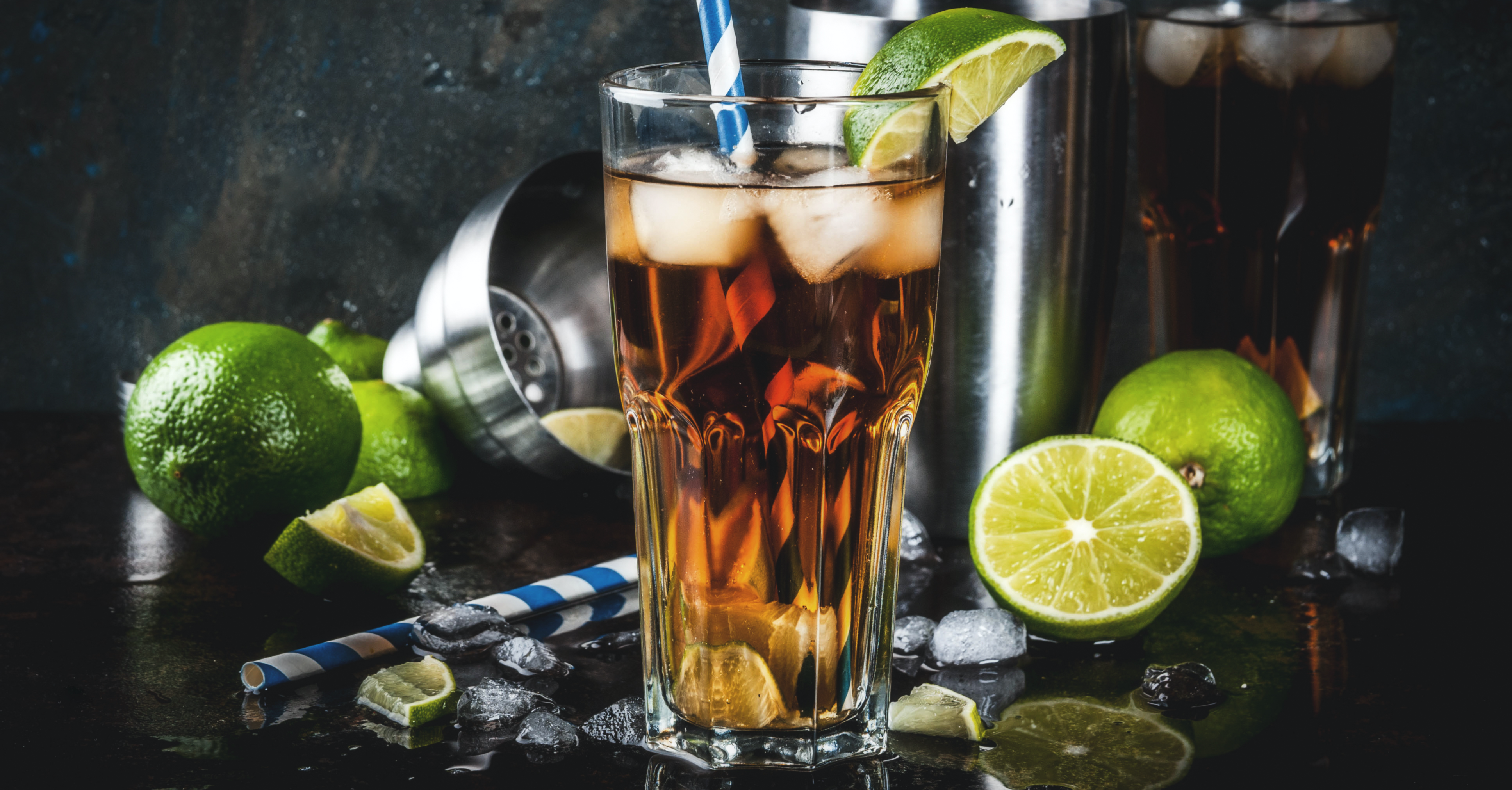 Golden highball cocktail in tall glass with floating ice cubes and fresh lime wedge