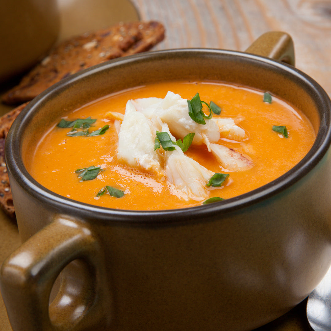 Shellfish bisque in a two handled pot with chunky white fish and fresh chopped parsley