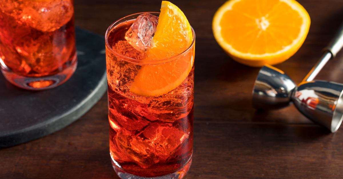 Americano cocktail in a highball glass with plenty of ice and a fresh slice of orange