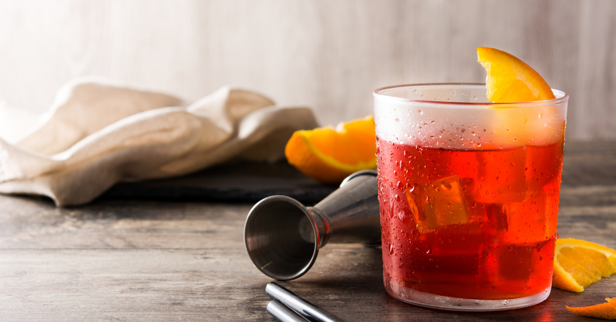 Rose negroni with square ice cubes and orange slice in a straight tumbler